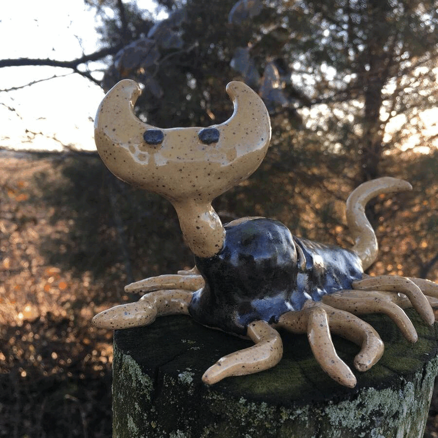 gif of a ceramic wayne larva from the game ‘hylics 2.’ it spins atop a mossy wooden fencepost